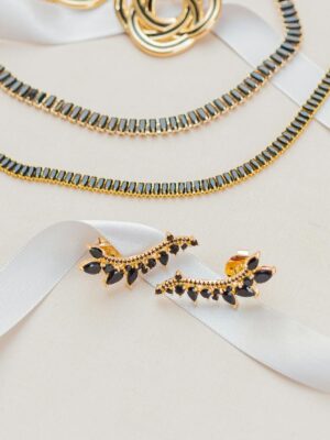 A sophisticated gold jewelry set displayed on a white ribbon, highlighting elegance and luxury.